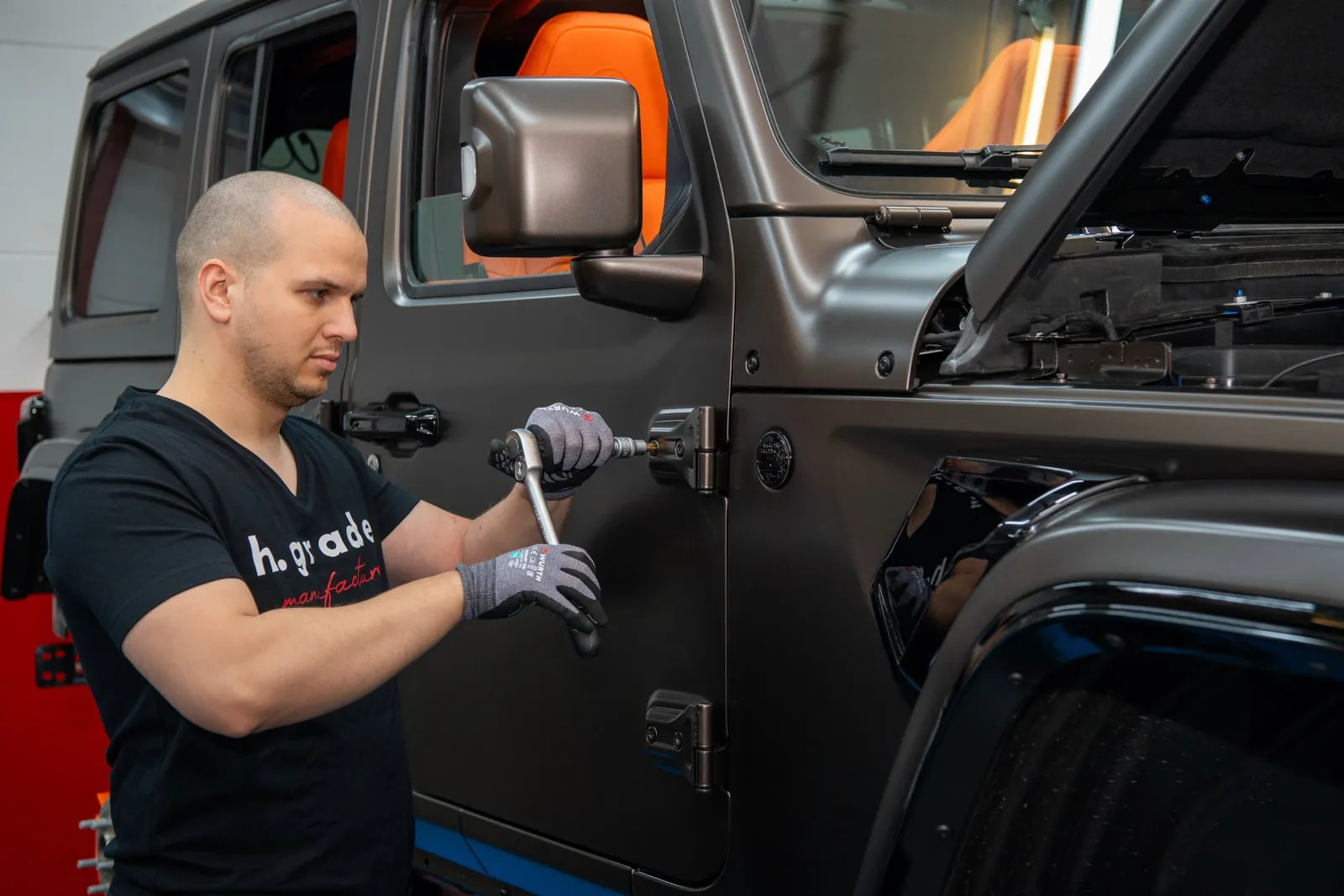 Techniker von h.grade montiert ein Bauteil am Kotflügel eines Jeep Wrangler in der Werkstatt.