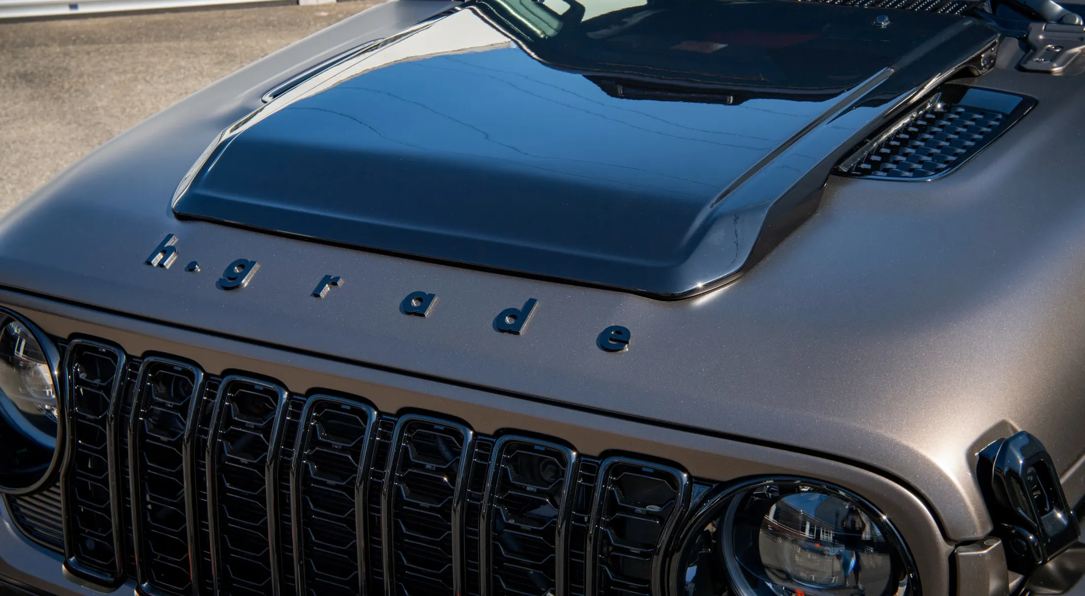 Motorhaube eines von h.grade veredelten Jeep Wrangler: Hutze, aufgesetzter h.grade-Schriftzug und schwarzer Kühlergrill.
